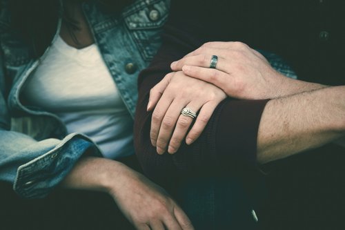 Hands of people sitting arm in arm.