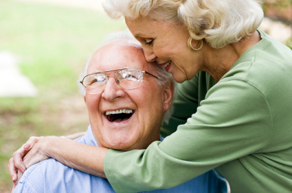 Husband has a big smile on his face while his wife hugs him.